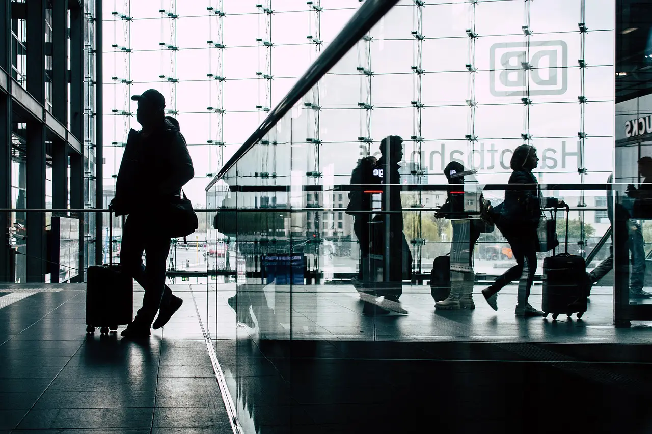 Reisende am Bahnhof im Gegenlicht - Die Kunst des Wartens – was Bahnhöfe über Städte verraten
