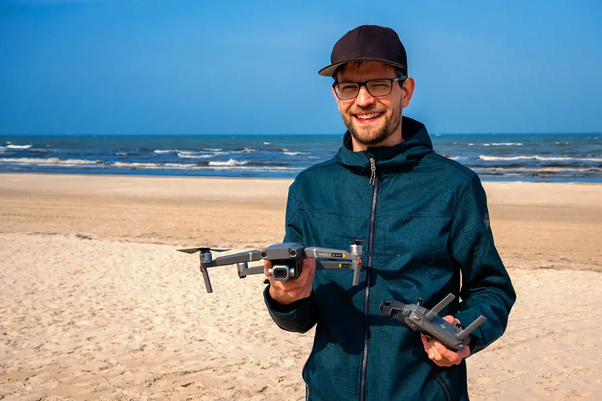 Mann mit DJI-Drohne am Strand der Ostsee – Drohnenflug im Urlaub mit Tipps und Länderregeln von Drohnen-Camp.de.