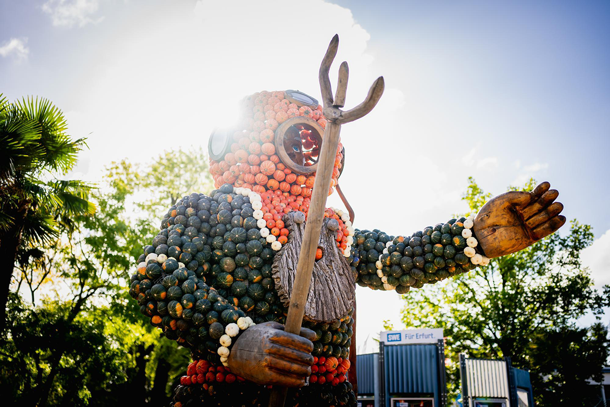 Große Figur aus orangefarbenen und grünen Kürbissen mit Dreizack bei der Kürbisausstellung im egapark Erfurt in Thüringen.
